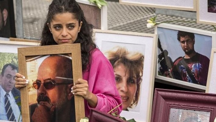 السورية وفاء مصطفى تجلس بين صور ضحايا النظام السوري وهي تحمل صورة والدها خارج مبنى محكمة كوبلنز غربي ألمانيا في 4 حزيران 2020